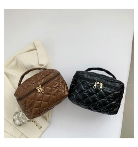 Dettaglio di borse da trucco in nylon trapuntato marrone e nero con cerniera dorata