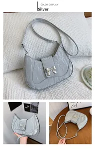 Detail of silver metallic crescent bag featuring pleated texture and silver bow buckle