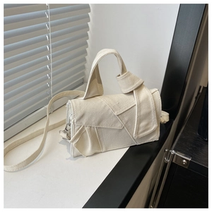 Detail view of cream canvas crossbody bag with unique knot handle and patchwork design