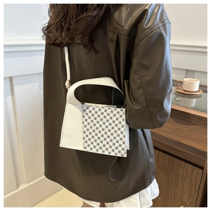 Sac à bandoulière blanc à motif géométrique porté par un mannequin dans un café élégant
