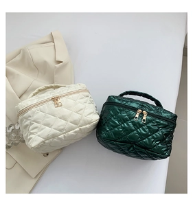 Dettaglio di borse da trucco trapuntate in beige e verde scuro con finitura seta