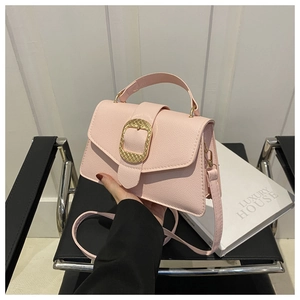 Detail of pink crossbody bag featuring a large matte gold buckle and textured leather finish