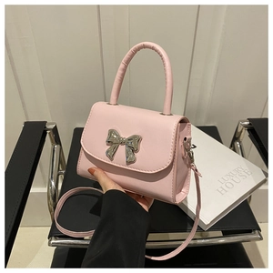 Detail of pink PU leather handbag with silver bow metal buckle and curved top handle