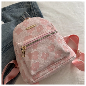 Details des rosa Mini-Rucksacks mit geprägten Blumen und goldenen Metallbeschlägen
