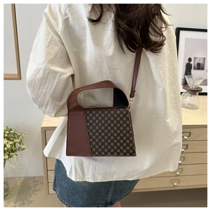 Détail du sac bandoulière vintage à motif damier porté dans un décor intérieur élégant