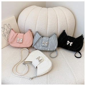 Detailed view of fashionable bow-knot metallic decor on crescent-shaped leather bags