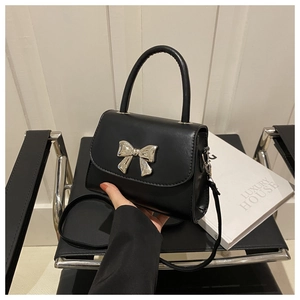Close-up of black PU leather bag featuring a silver metal bow buckle and round handle