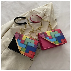 Detail of color-block geometric chain crossbody bags with gold hardware on a blazer