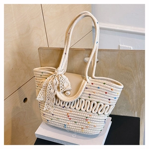 Detail of woven straw tote with colorful dots, pearl clasp and lace bow charm