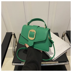 Detail of green litchi grain leather bag with a large gold oval buckle and top handle