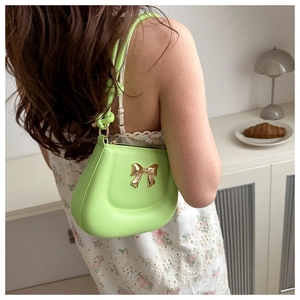 Detail of trendy neon green handbag with gold bow buckle shown in a stylish indoor setting