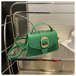 Detail of emerald green lychee leather bag with gold buckle and adjustable strap