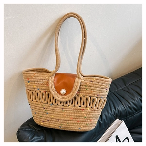 Close-up of woven straw tote with colorful yarn, leather flap and large pearl buckle