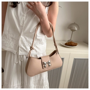 Dettaglio della borsa hobo in pelle beige con fibbia a fiocco argento e tracolla annodata