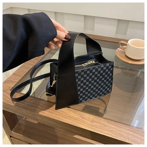 Gros plan du sac à main bleu à motif losanges avec poignée noire sur une table en bois