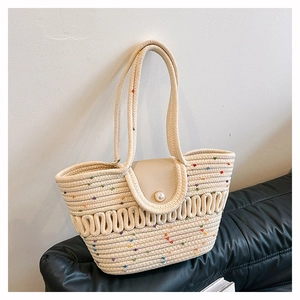 Detail of woven straw tote bag featuring a pearl clasp and elegant wavy texture