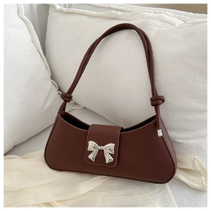 Close-up of chocolate brown shoulder bag featuring silver bow hardware and knot details