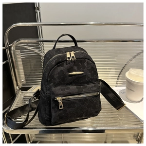 Detail eines schwarzen Mini-Rucksacks mit floralem Stoff und goldenen Reißverschlüssen
