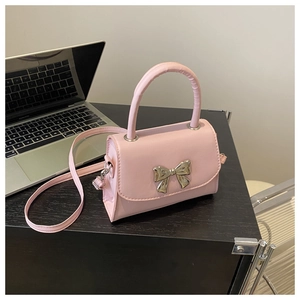 Close-up of pink PU leather crossbody bag featuring a silver metal bow accent