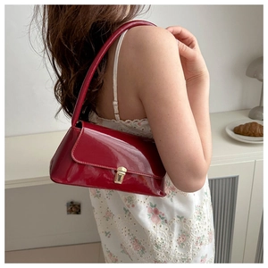 Detail view of red patent leather baguette bag with gold metal buckle on female model