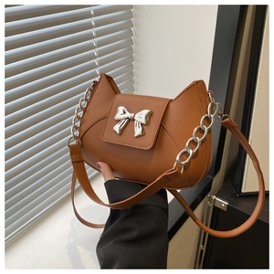 Dettaglio di una borsa in pelle marrone con fibbia a fiocco in argento e catenella