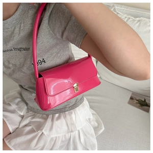 Detail of rose pink patent leather baguette bag with golden metal buckle on shoulder