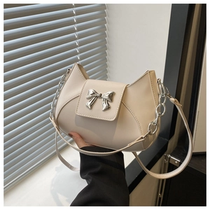 Dettaglio borsa a tracolla beige crema con fiocco in metallo argento e catena
