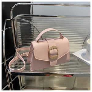 Detailed view of pink lychee leather texture and golden metal buckle on a shoulder bag