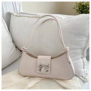 Detailed close-up of cream faux leather baguette bag with silver bow buckle