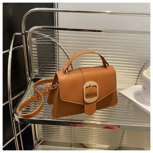 Detail of vintage caramel brown leather bag with elegant golden woven metal buckle