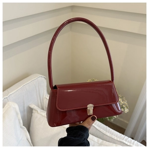 Detail of burgundy glossy patent leather shoulder bag with silver metallic buckle closure