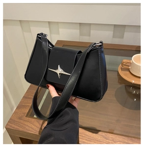 Detail of minimalist black leather underarm bag featuring a silver star metal buckle