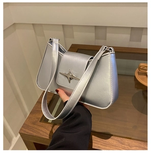 Detailed view of silver metallic shoulder bag with shiny star hardware and flap closure
