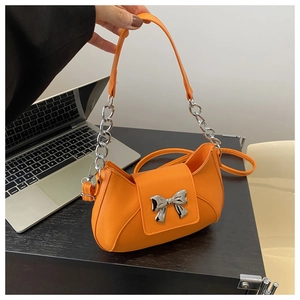 Dettaglio borsa arancione in pelle PU con fiocco in metallo argentato e tracolla a catena