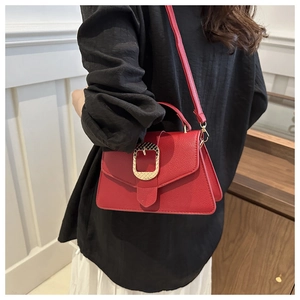 Red pebbled leather crossbody bag with gold buckle shown on a model for scale