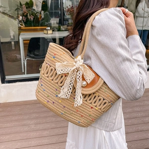 Woven straw beach tote with colorful dots, pearl clasp, and lace bow detail