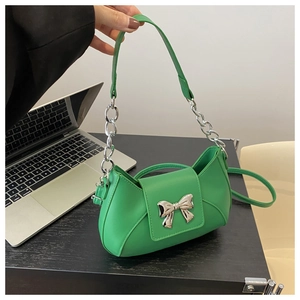 Dettaglio borsa a tracolla verde con grande fiocco in metallo argento e catena spessa
