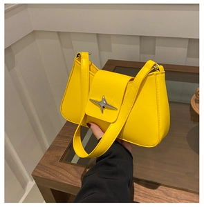 Detailed close-up of bright yellow shoulder bag with star metal buckle and smooth texture