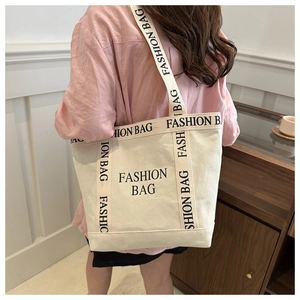 Détail d'un grand sac fourre-tout en toile à lettres avec bandoulières et design minimaliste