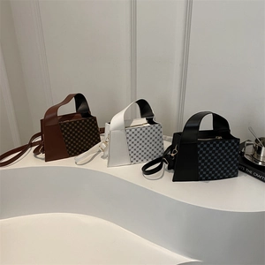 Trois petits sacs à main carrés minimalistes en marron, crème et noir sur support blanc