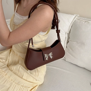 Retro dark brown baguette bag with silver bow accent shown in a cozy indoor setting