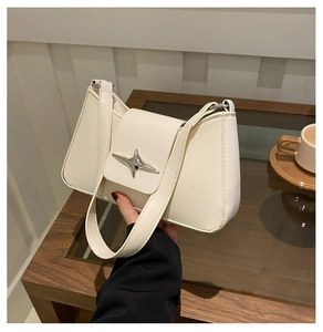 Detail of minimalist beige faux leather shoulder bag with a silver star-shaped metal buckle