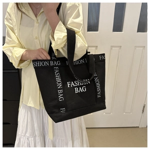 Detail of black canvas tote bag featuring white FASHION BAG letters and large capacity