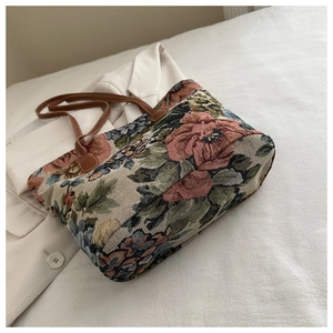 Macro view of vintage floral jacquard fabric and brown leather strap on tote bag