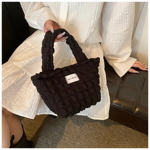Detail of black puff textured tote bag with a LOVE FASHION label and soft fabric handles