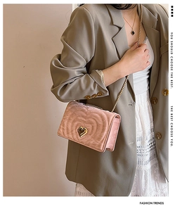 Detail of pink heart-quilted crossbody bag featuring gold heart clasp and chain strap