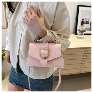 Detail of pink faux leather crossbody bag with gold metal buckle and pebble texture