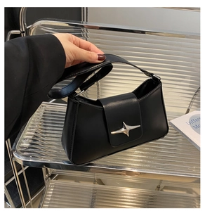 Close-up of black minimalist underarm bag featuring silver star hardware and leather strap