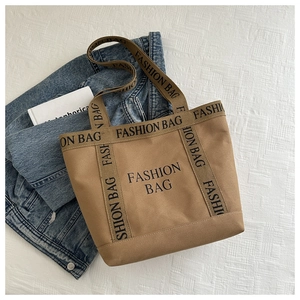 Détail du sac cabas en toile kaki avec lettrage FASHION BAG et anses solides