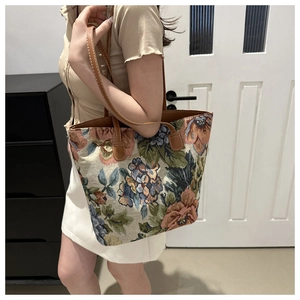 Detail of floral tapestry fabric and brown leather strap on a large tote shoulder bag